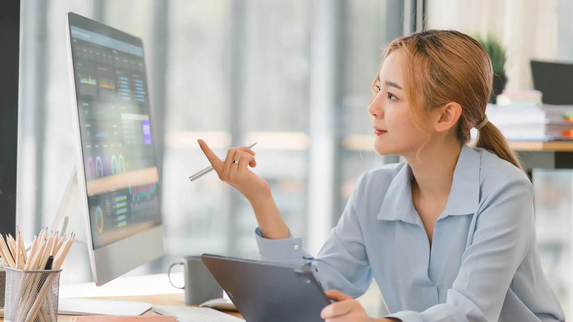 asian lady looking at computer screen thinking and analyzing data